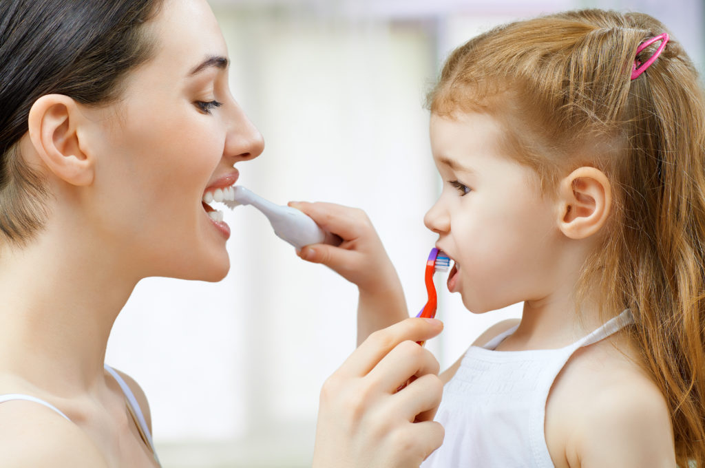 Mom and daughter brushing each others' teeth