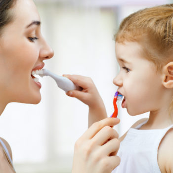 Mom and daughter brushing each others' teeth